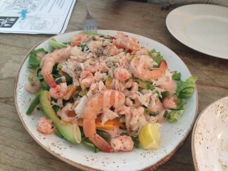 a salad is served with shrimp, avocado and lettuce