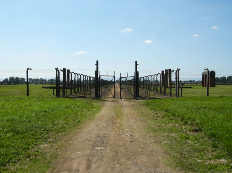 an open road leading to a gate that has been set up in the middle of a grassy field