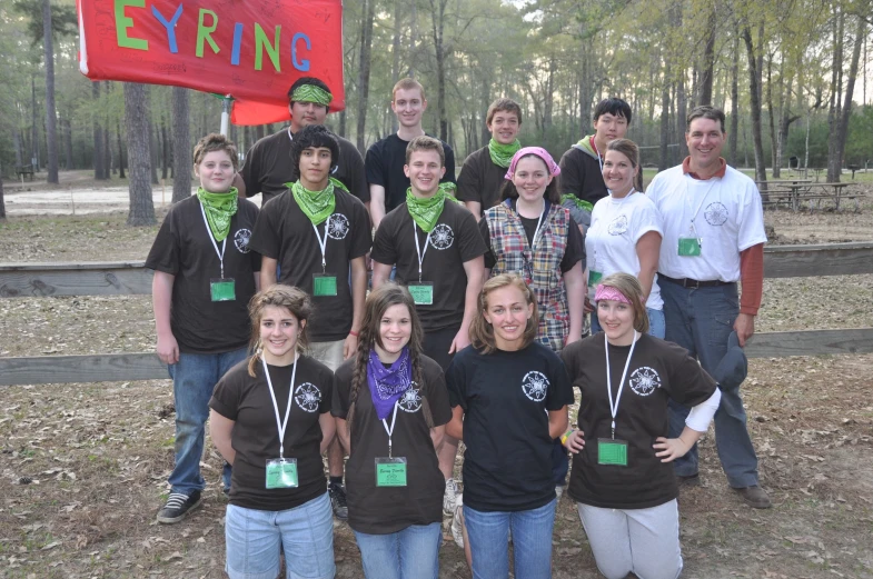 a group of people posing with other people in front of a red flag