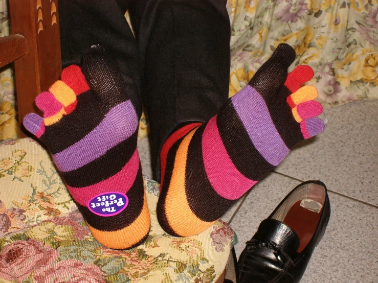 a woman with colorful socks and slippers with her foot up