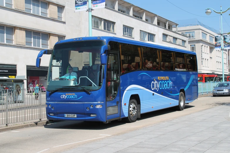 a blue bus parked at the curb next to a sidewalk