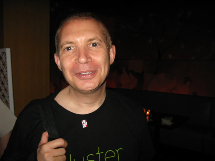 a man in a black shirt smiles at the camera
