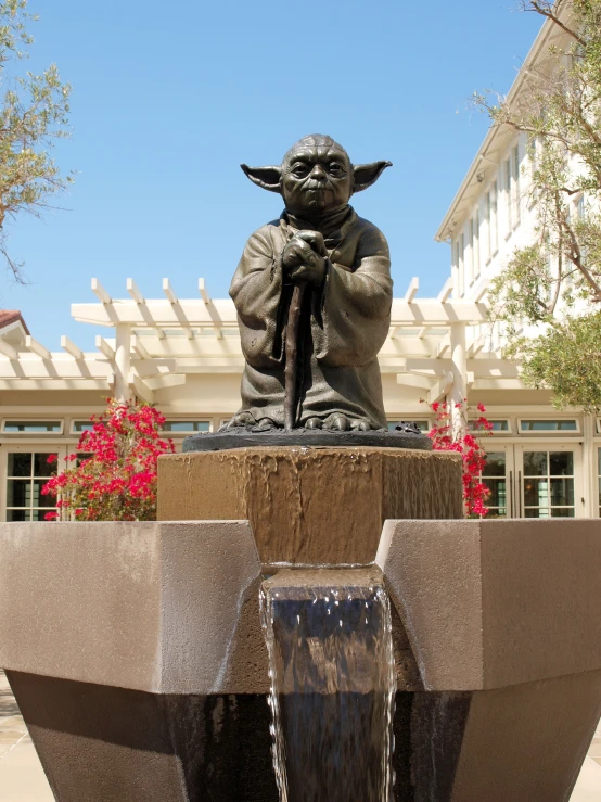 a statue of a yoda with a fountain running in front of it