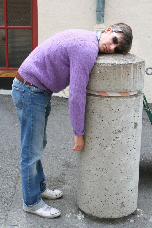 the young man is leaning on a cement object