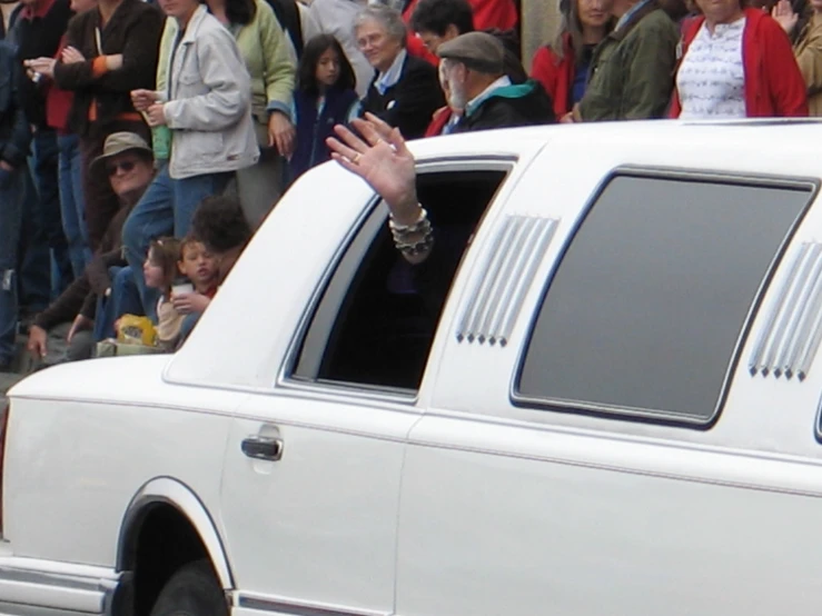 a white car parked in front of a crowd of people