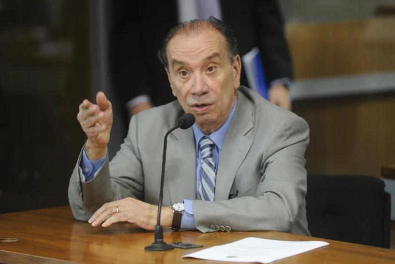 a man in a suit and tie speaking on a microphone