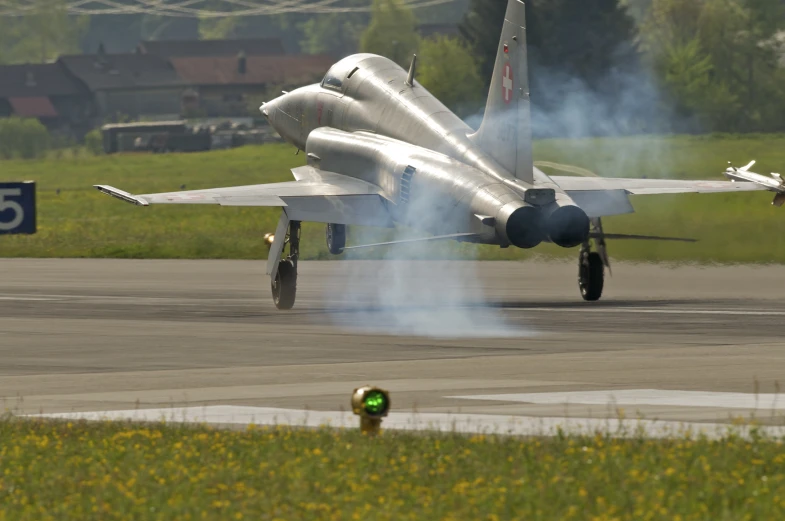 a large silver plane on a runway with some people around it