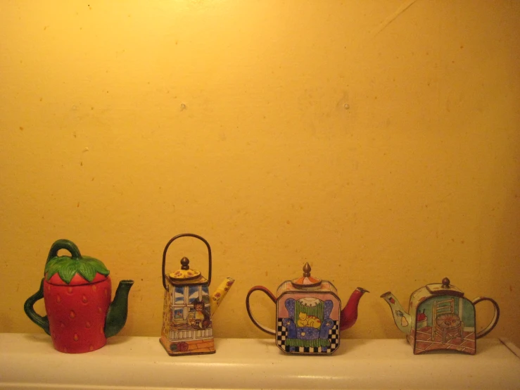 several teapots sitting next to a pot, kettle and a pan