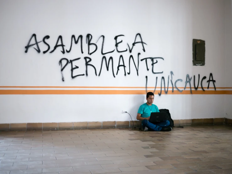 the young man sitting on the floor has some writing on his wall