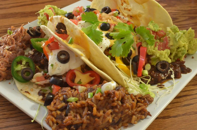 a plate topped with lots of tacos covered in beans and veggies