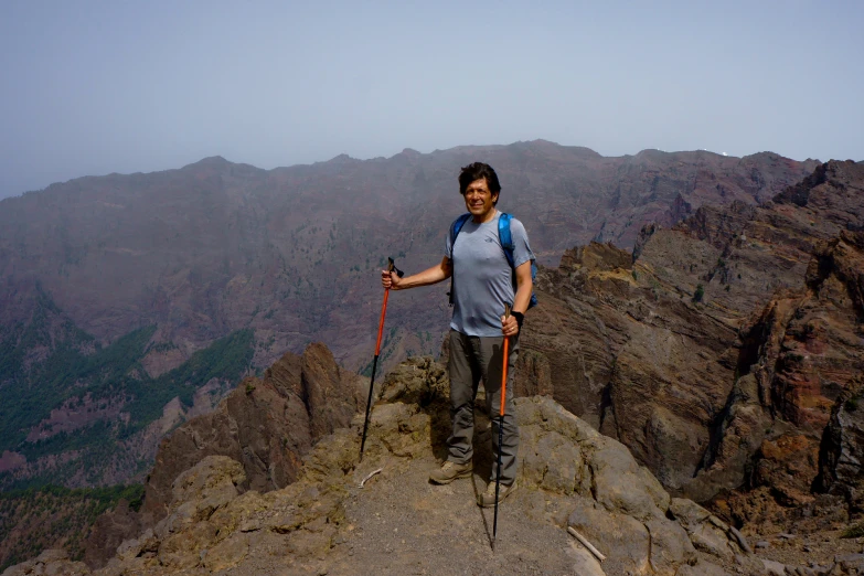 a man standing on the side of a mountain holding his hiking poles