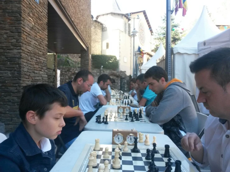 people are sitting at tables playing chess outside