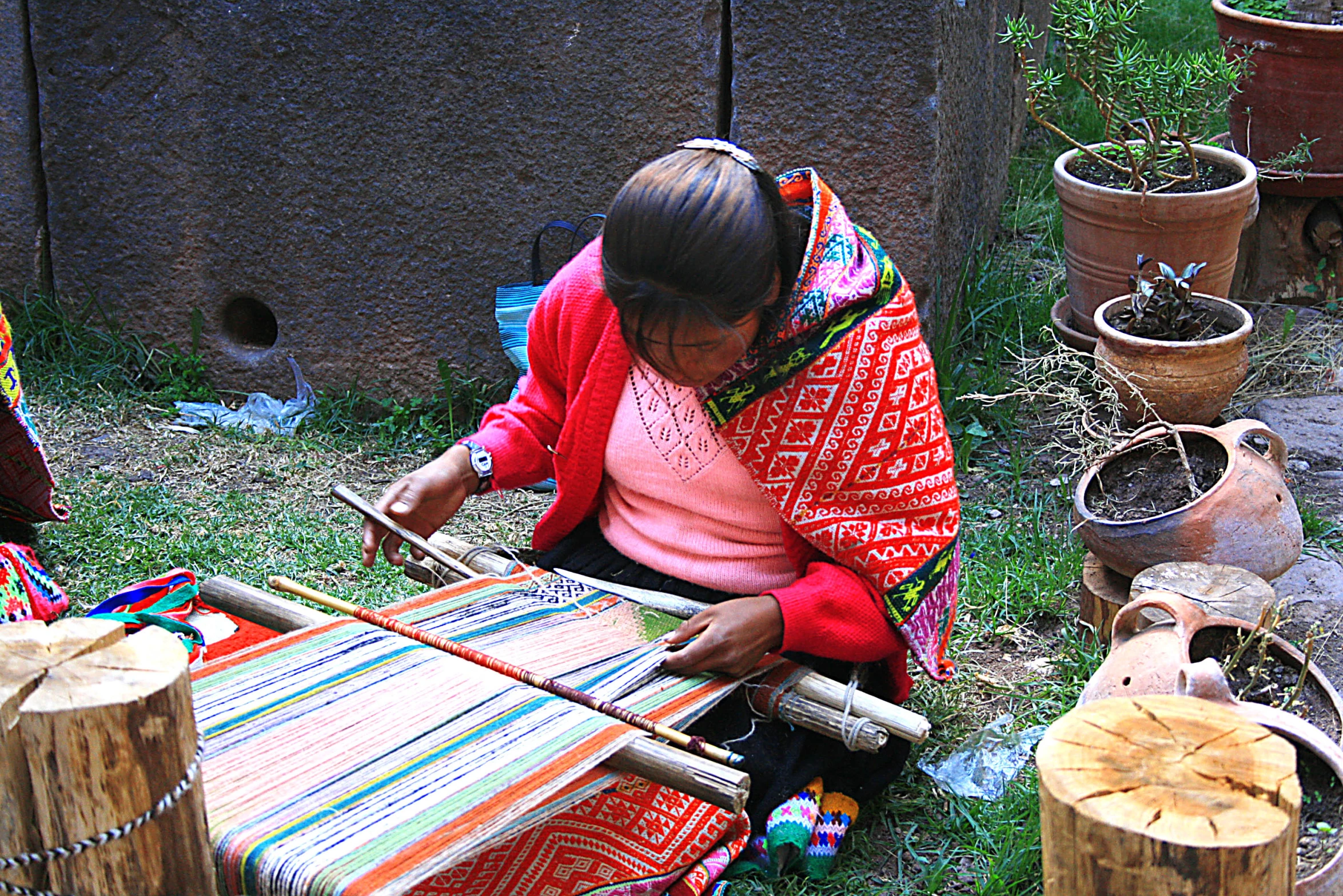 a woman making blankets sitting next to trees