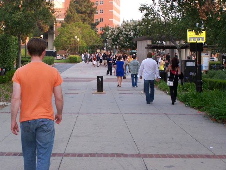 a man in an orange shirt looking at a crowd of people