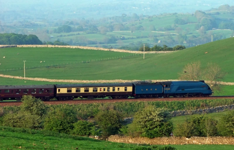 a train is moving down the tracks in the mountains