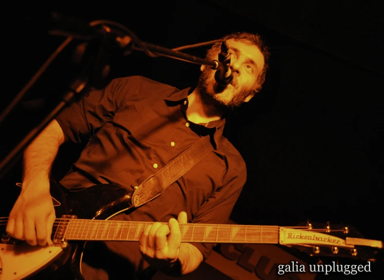 a man holding a guitar playing an acoustic instrument