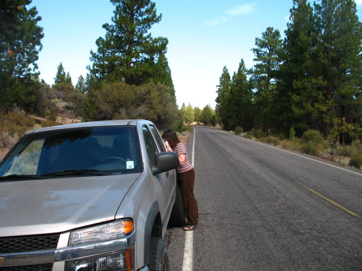 a woman is leaning on the front of a car