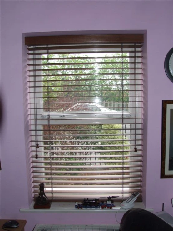 a window in the middle of a purple room with wood blinds