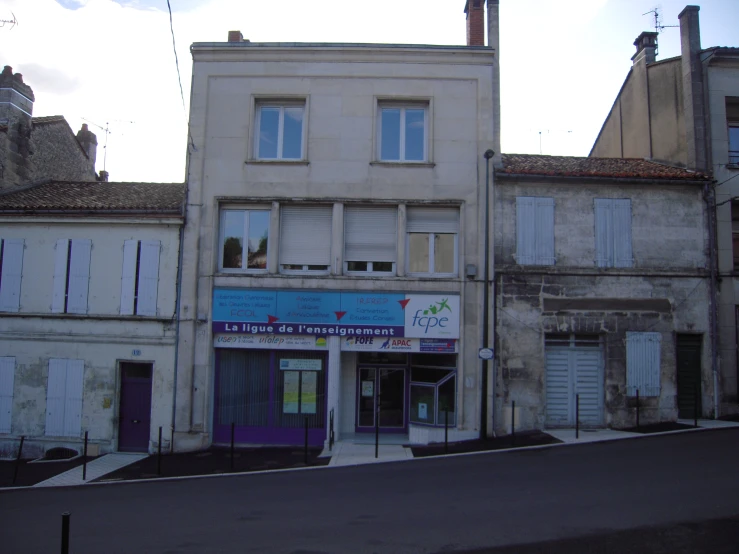 an older building with a closed door on the sidewalk