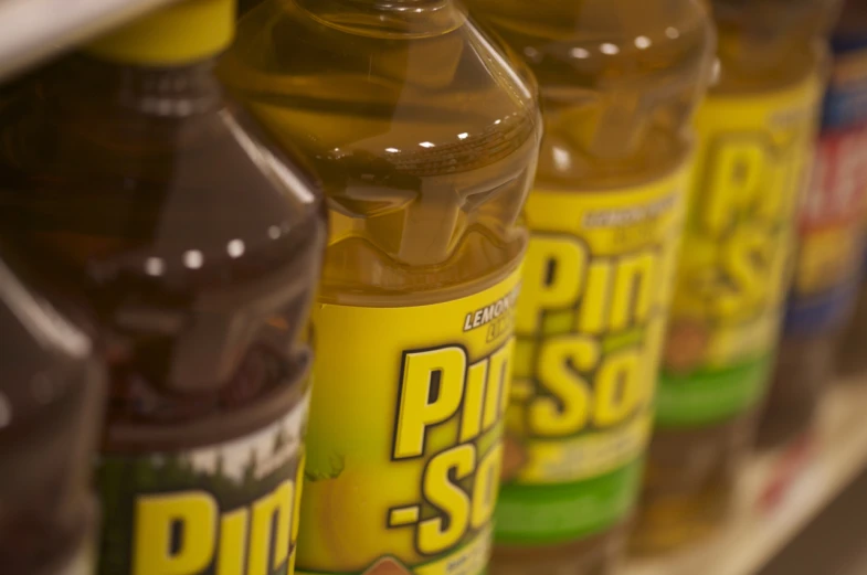 many different bottles and containers of oil are stacked on a shelf