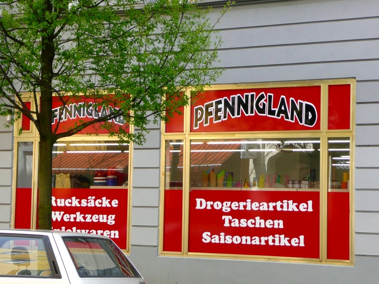 a store front with a tree outside and some signs above the windows