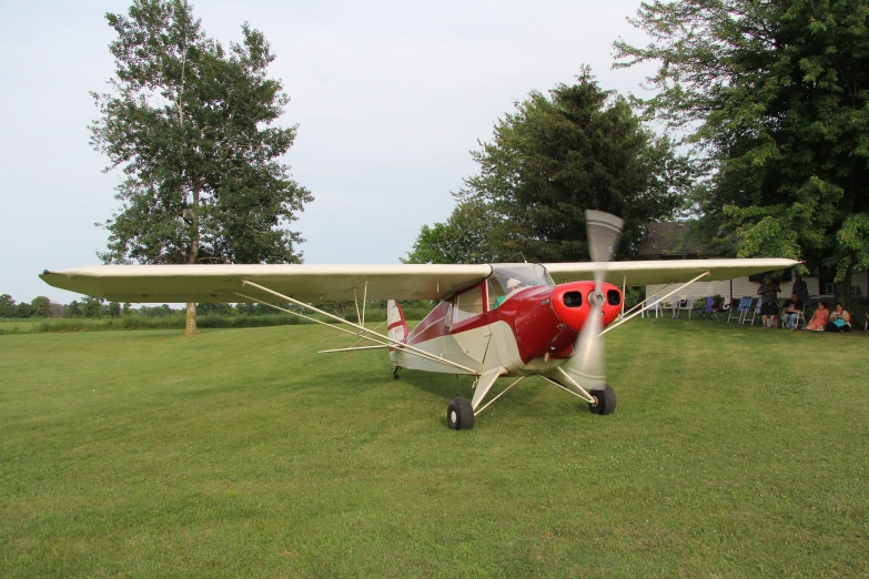 a small red and white plane is sitting in the grass