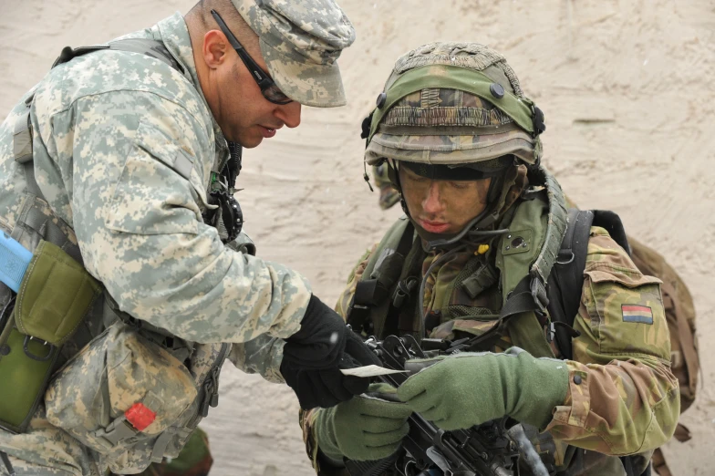 an army soldier is examining soing on another soldier