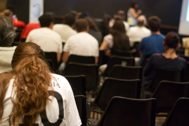 a person sitting at a lecture hall listening to someone