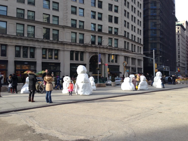 some people walking near big snowmen on a street