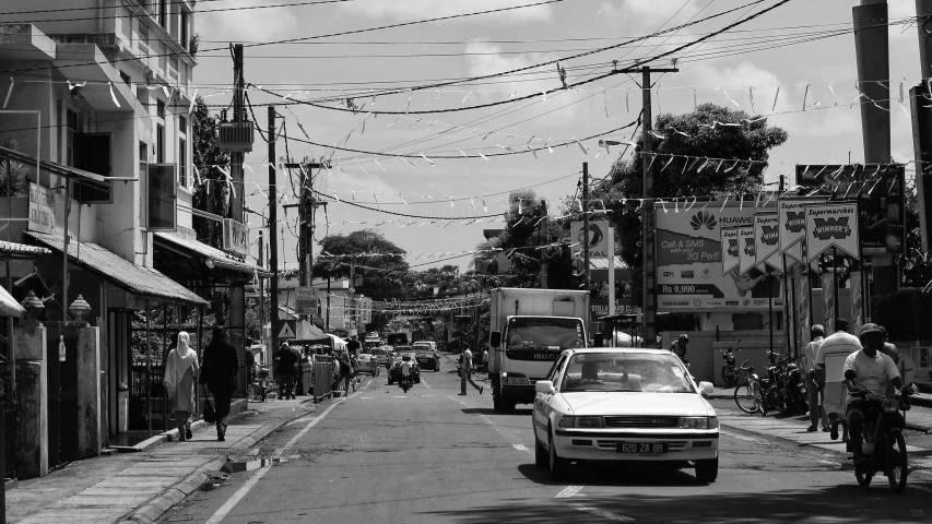 cars drive down the street past pedestrians on bicycles