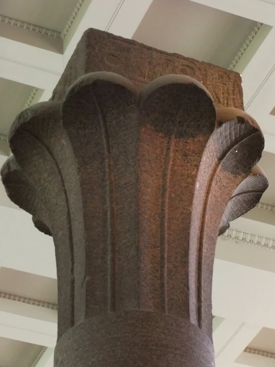 an ornate corinular carved stone pedestal against the ceiling