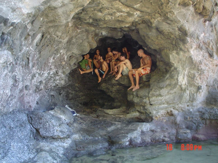 group of friends lounging in natural cave on the side of a body of water