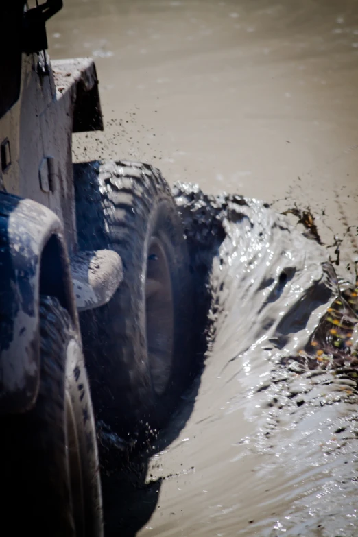 a blue truck stuck in a large amount of mud