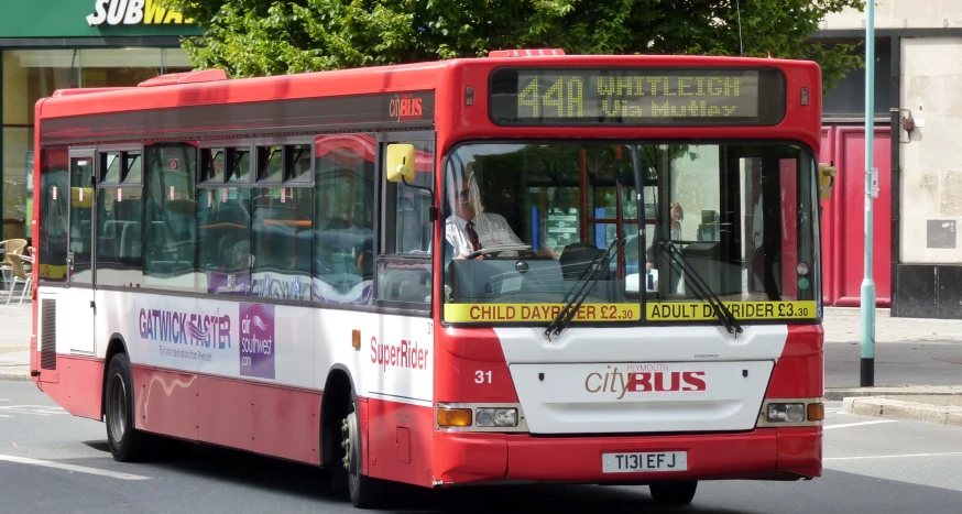 a red city bus driving on the road