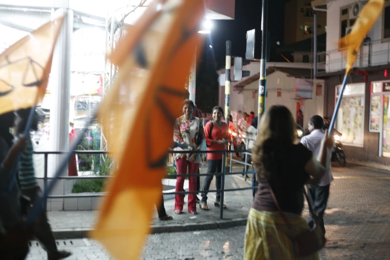 several people holding orange and black umbrellas at night