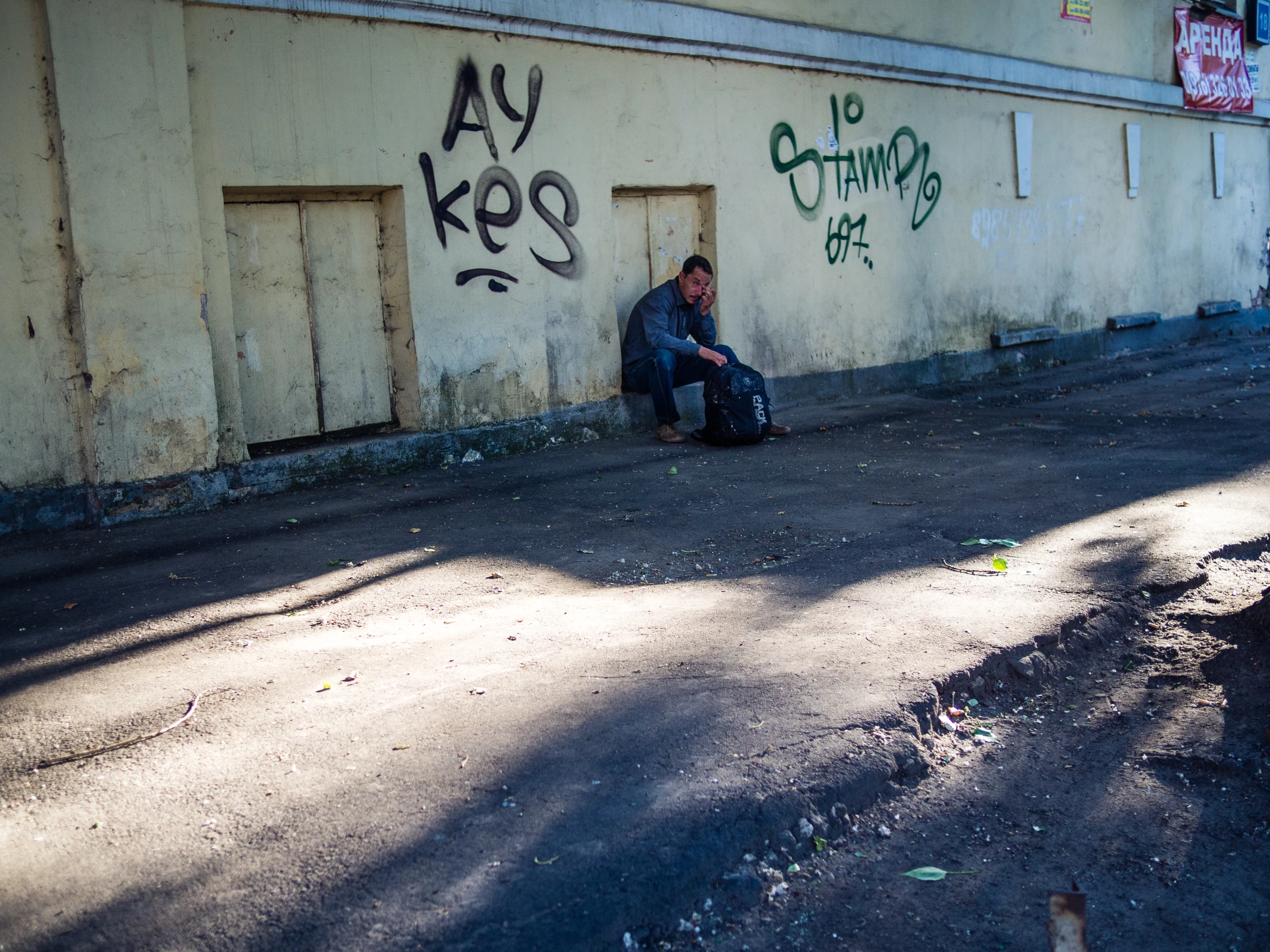 a man is sitting by the wall with his suitcase