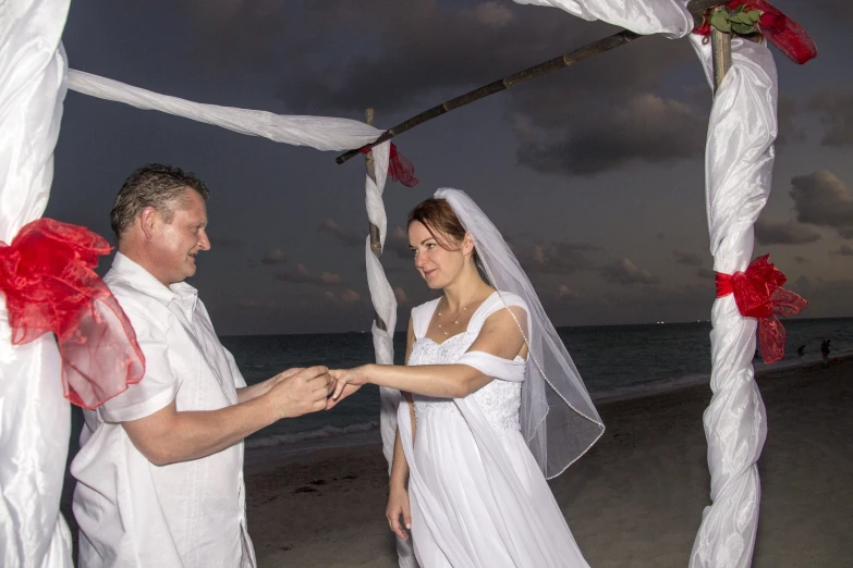 the bride and groom are exchanging vows on the beach