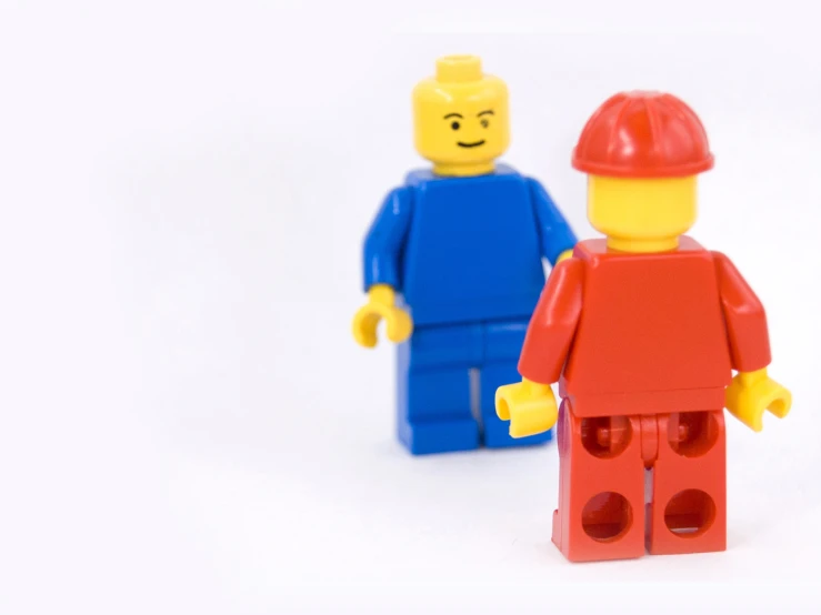 a close up of two lego figurines one with a red brick and the other blue