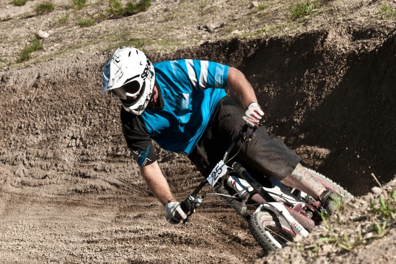 a downhill biker in a helmet and gloves is on a dirt bike track