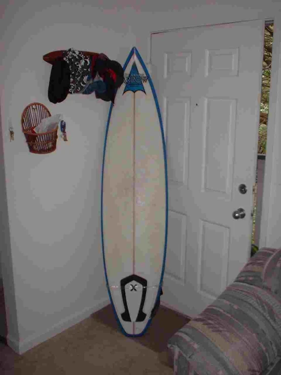 the white surfboard is standing in the living room