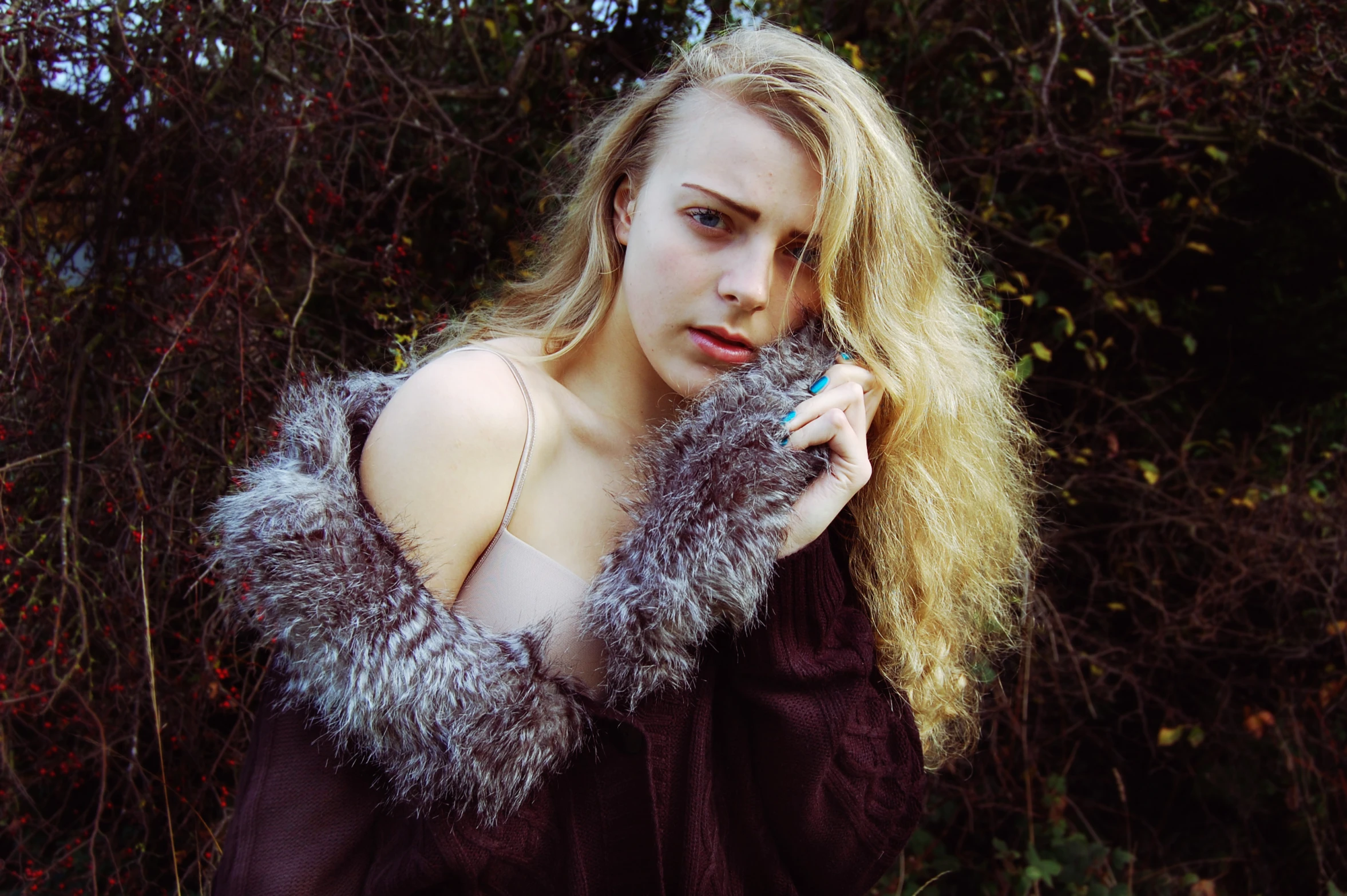 a woman holding a toothbrush wearing a fuzzy scarf