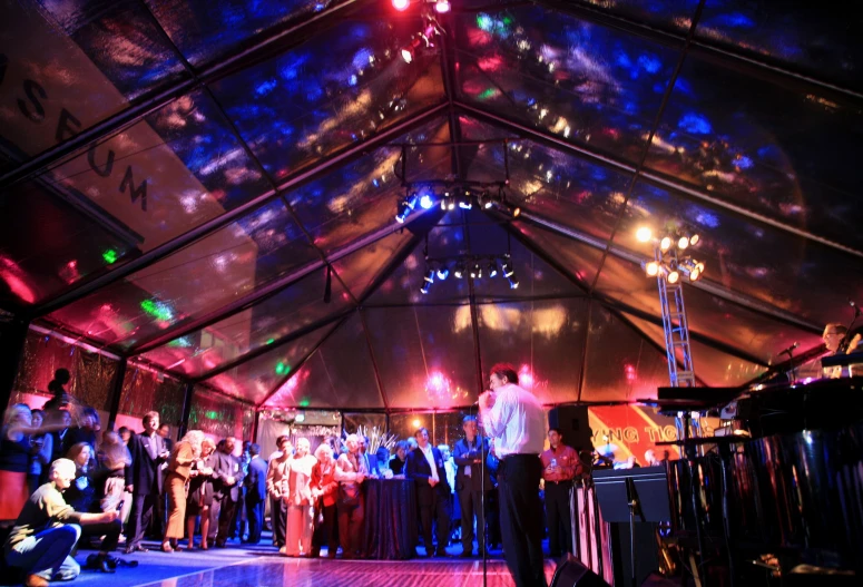 a large crowd under a tent filled with people