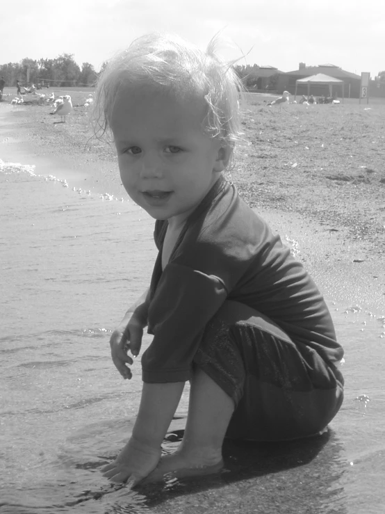 a baby is playing on the beach by the water