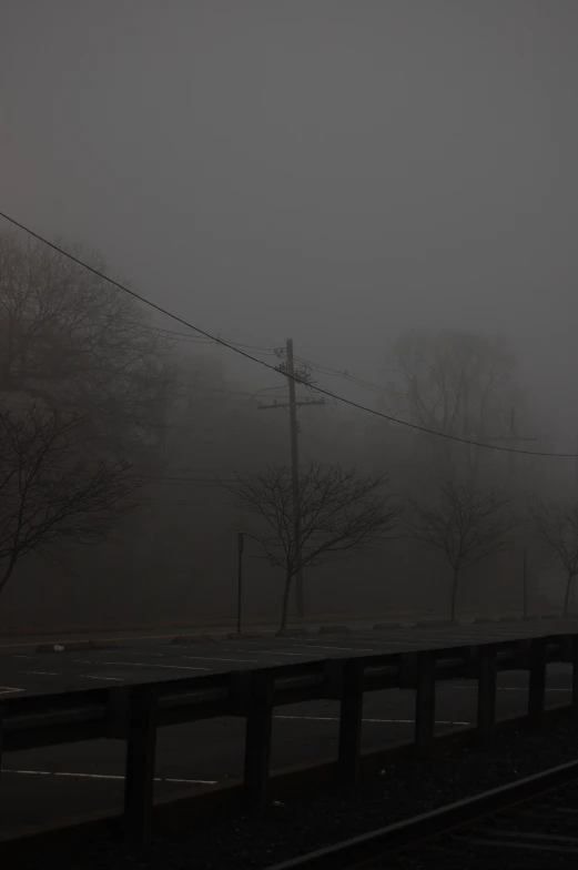 a foggy street that has a telephone pole and road signs on it