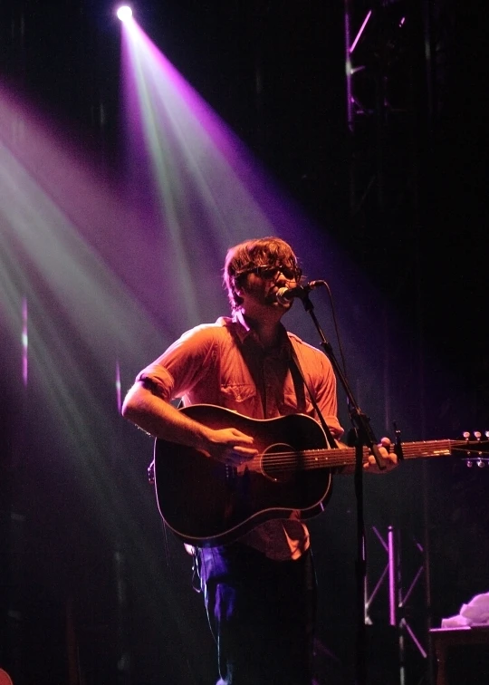 a man playing a guitar in a band of people