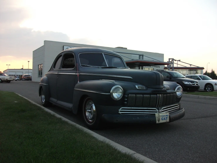 an old car parked in the lot in front of a building