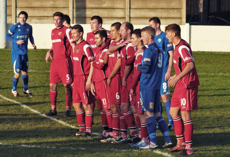 soccer players are standing on the sidelines, and they are looking at each other