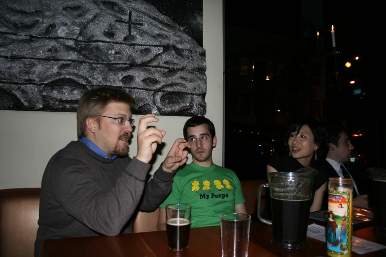 three people siting at a table with drinks in front of them