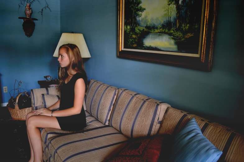 a woman sitting on a couch near a lamp