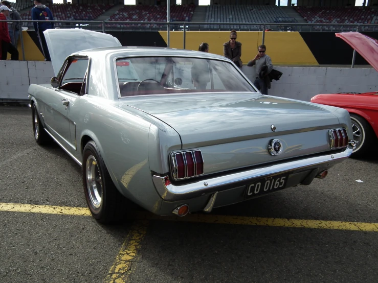 an old mustang sits parked in the parking lot